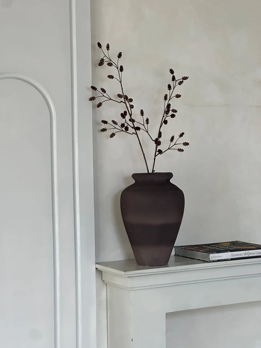 small terracotta-inspired antique pots styled on shelf with books and curated décor
