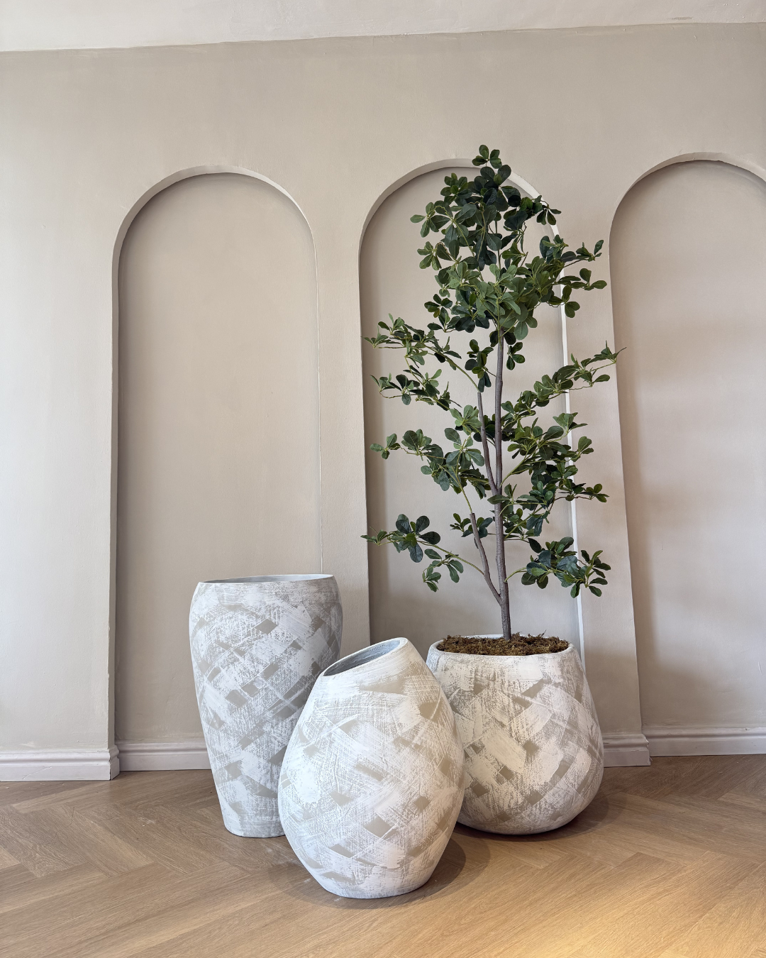 Monochromatic indoor plant arrangement featuring matching white decorative planters in large, medium, and small sizes, highlighting the height, texture, and beauty of premium artificial plants.