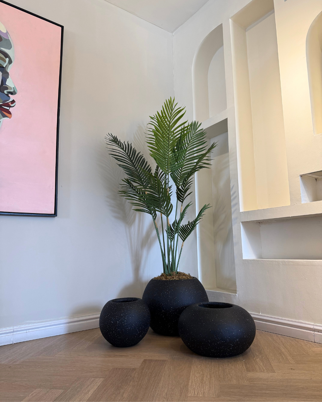 Indoor plant arrangement featuring white and black decorative planters that create purposeful contrast, highlighting premium artificial plants in modern living rooms, offices, and commercial interiors.